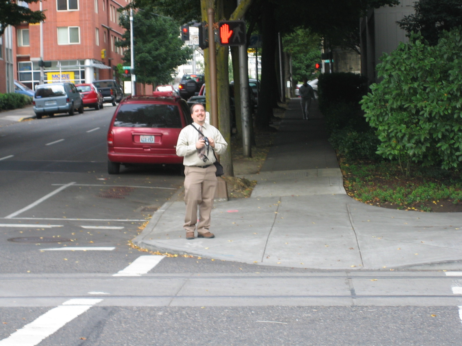 a man standing on a city sidewalk next to a red car