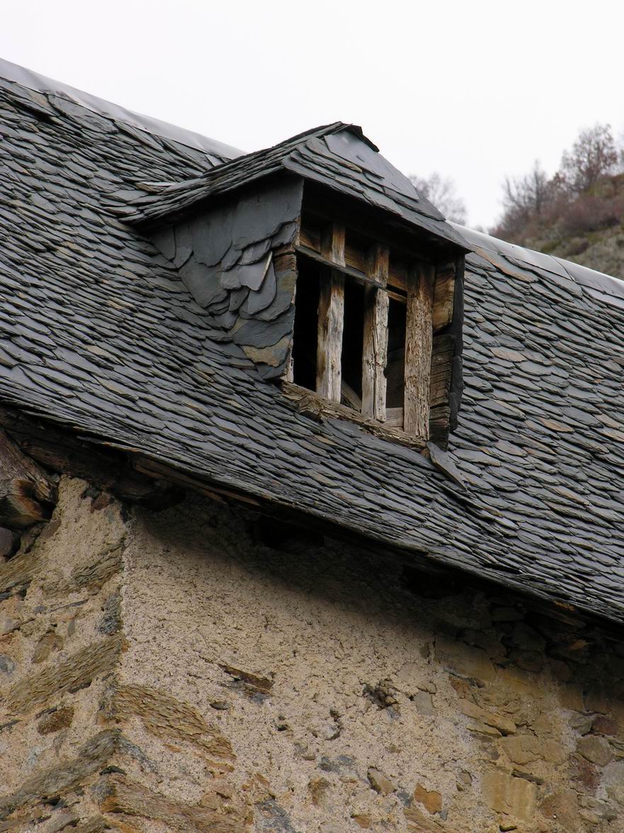 old windows with a brick roof and weather vein on a stone wall