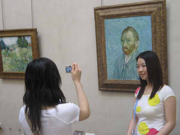 two women standing in front of paintings taking a po