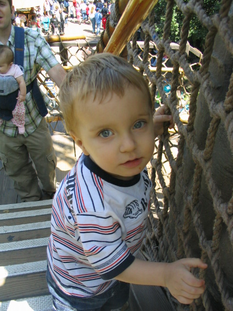 small boy with blonde hair standing on top of wooden steps