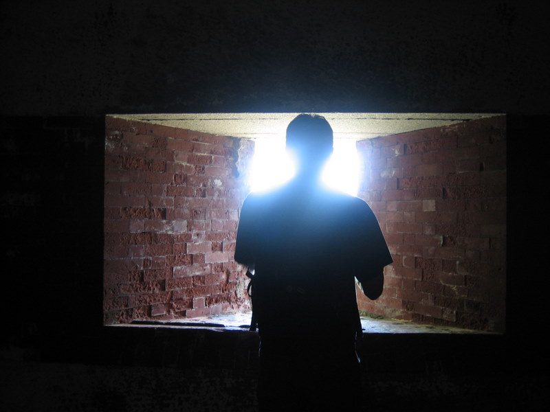 the silhouette of a person standing in front of an opening of a brick wall