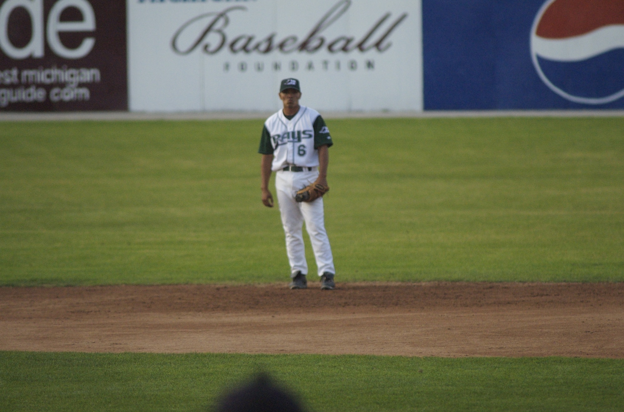 baseball player standing at the base after pitching the ball