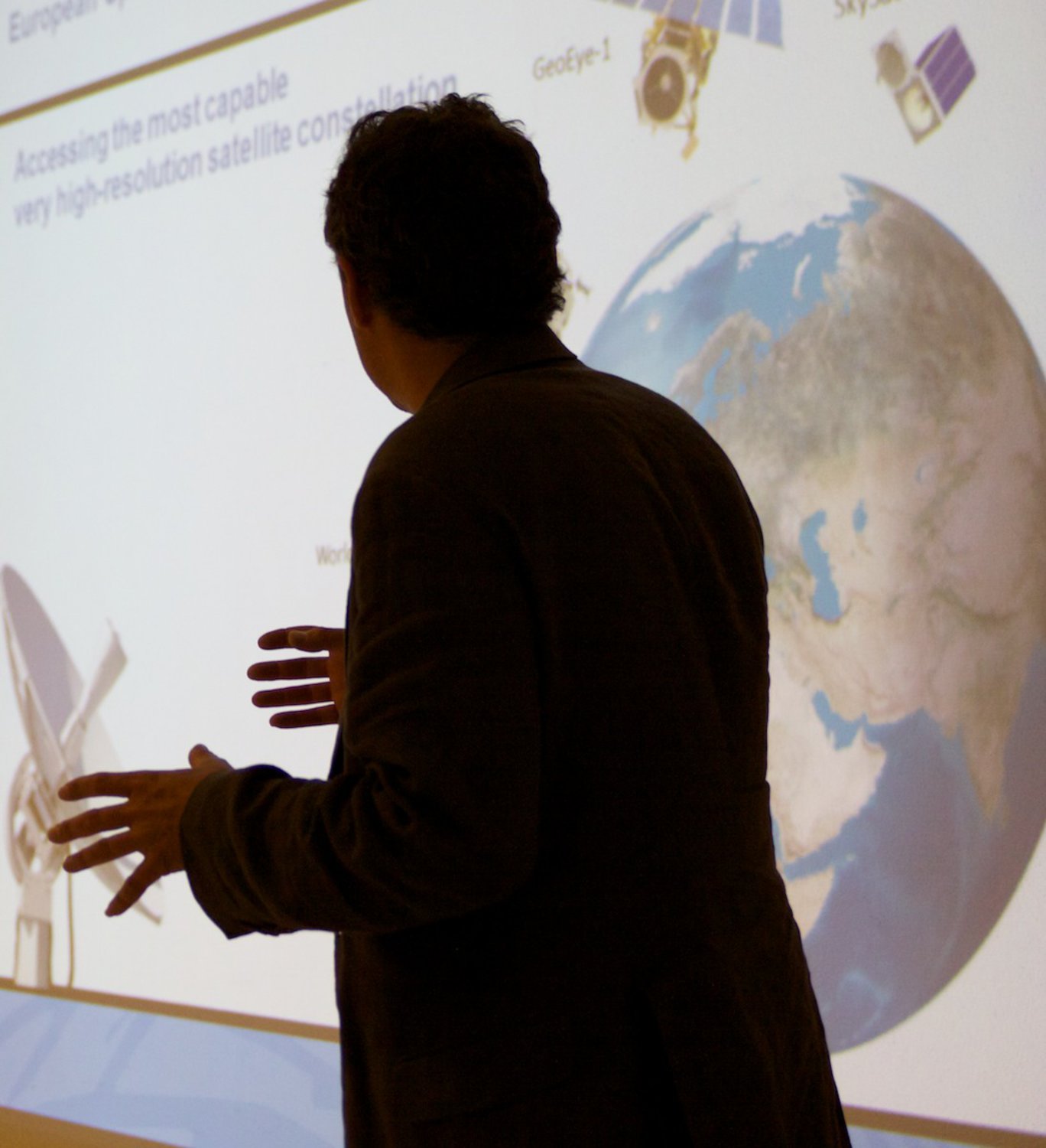 a man giving a lecture in front of a projected globe