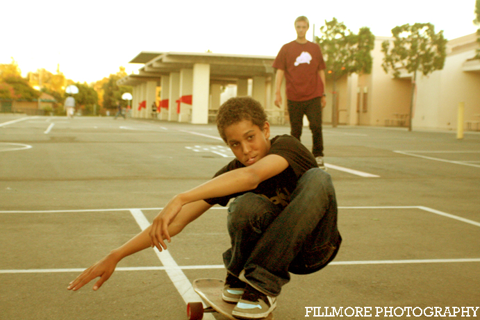 a young man riding a skateboard across a parking lot