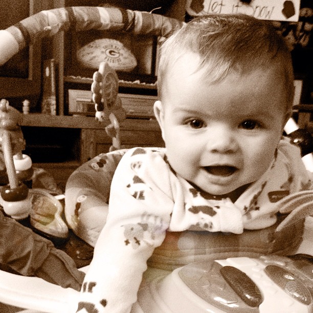 a young child sitting in a baby highchair with one foot on the seat