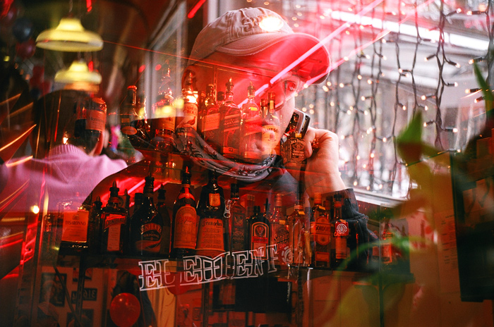 a man sitting behind a bar filled with bottles of liquor