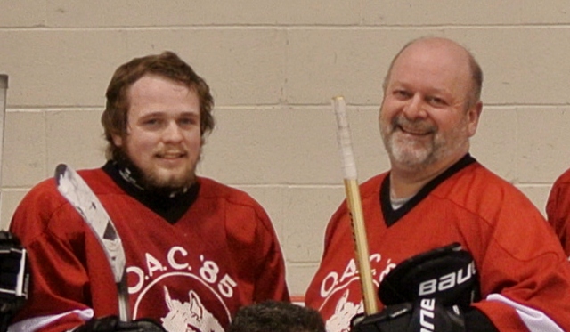 a couple of men that are standing together with hockey equipment