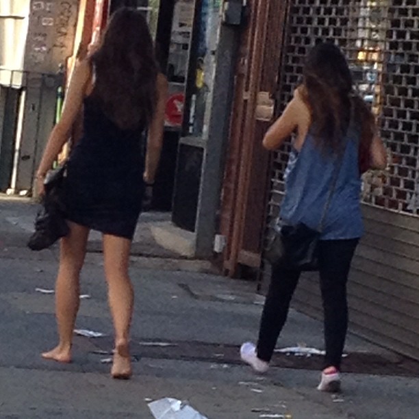 two woman walking down a street next to each other