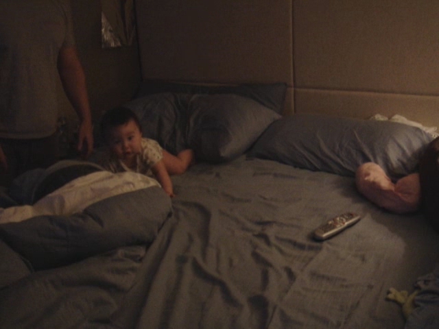 a child laying in bed with a man standing nearby