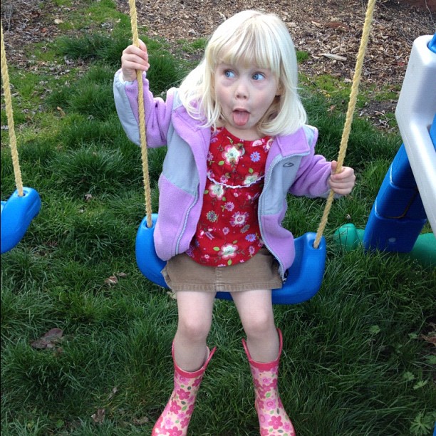 a little girl on a swing with her tongue out