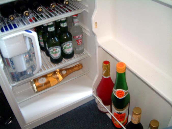 three bottles and two glasses sitting on an open fridge