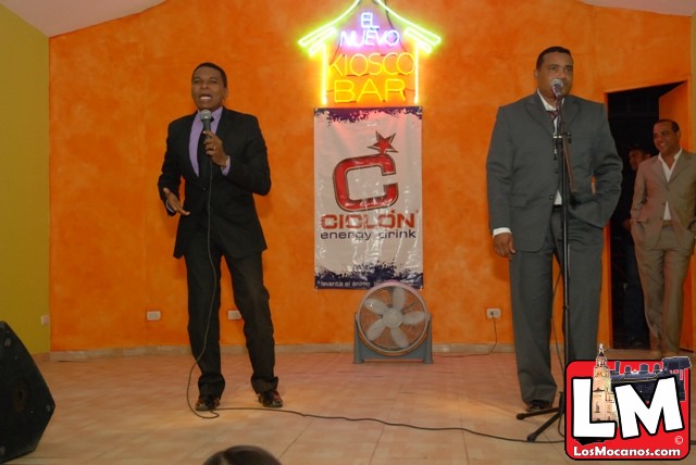 two men in suits stand at microphones, speaking