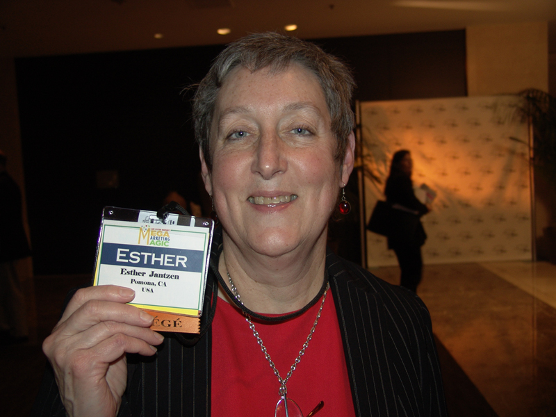 an old woman holds up her award while wearing a necklace