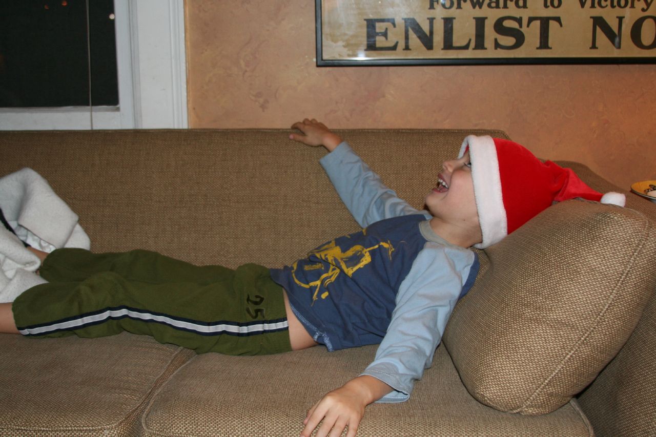 a little boy wearing a hat lying on the couch