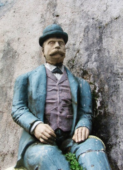 a statue of a man is sitting by a rock