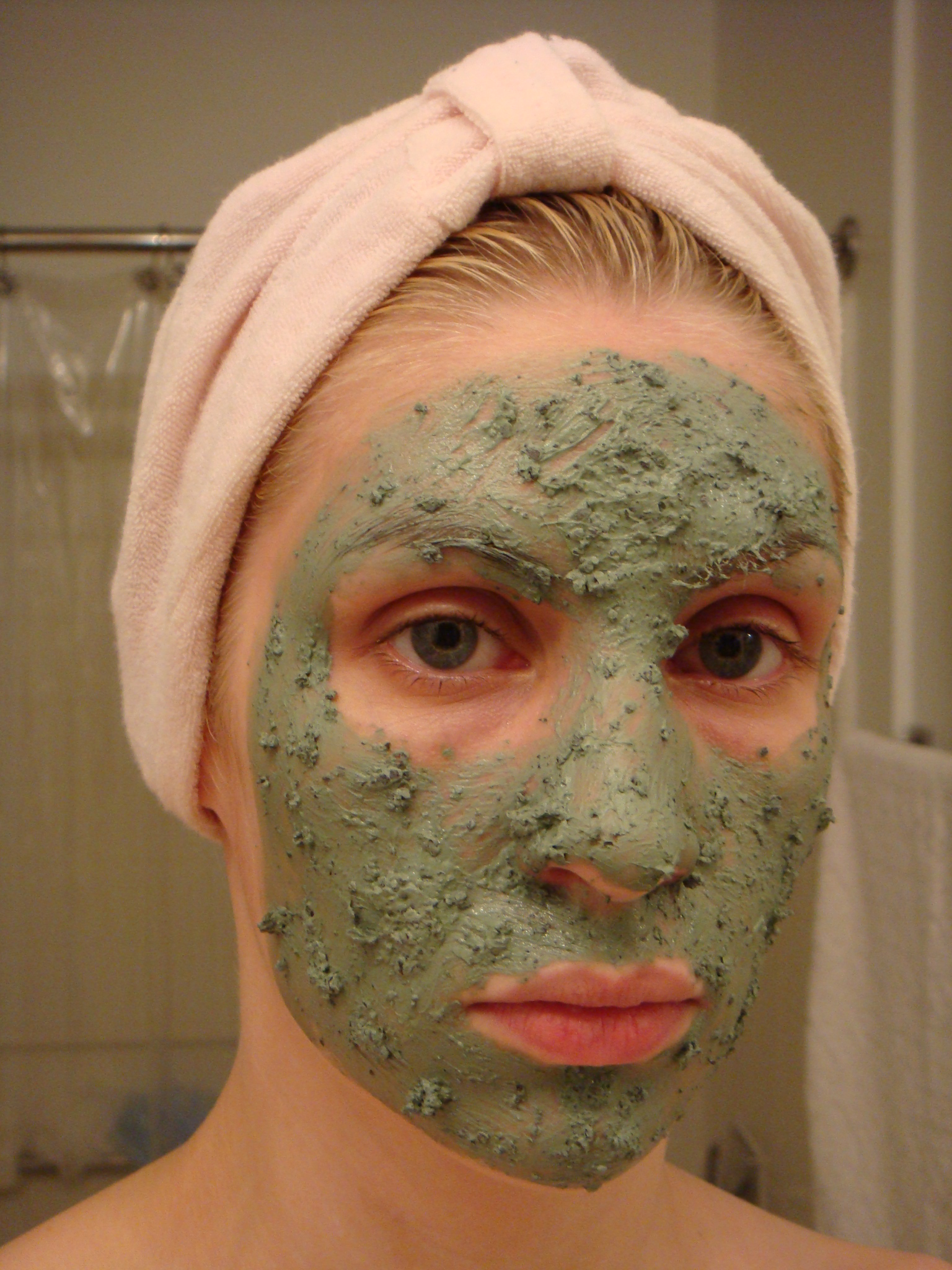 a woman with green facial mask in bathroom