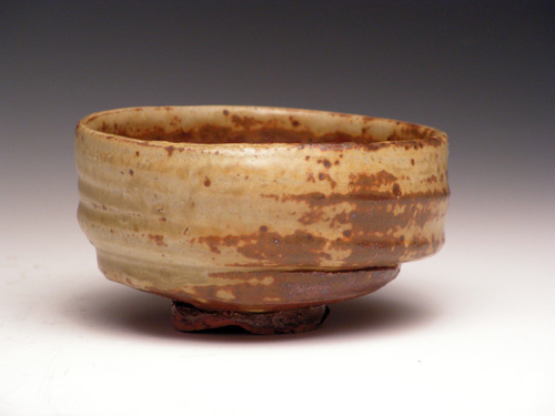 brown and white ceramic vessel sitting on a white surface