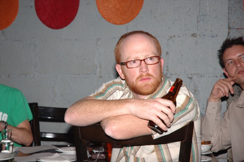 a man sitting at a table with a beer bottle