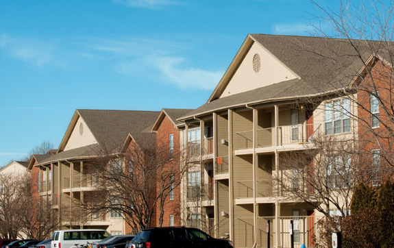 two large brick apartment buildings with cars parked outside the front doors