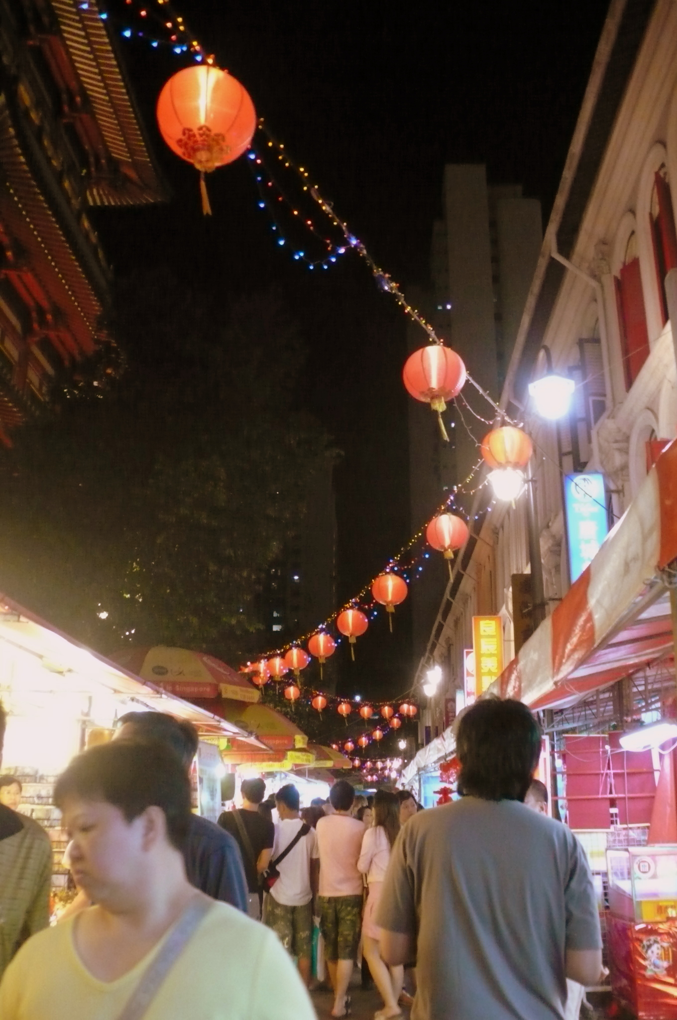 people walking down a crowded street lined with lanterns