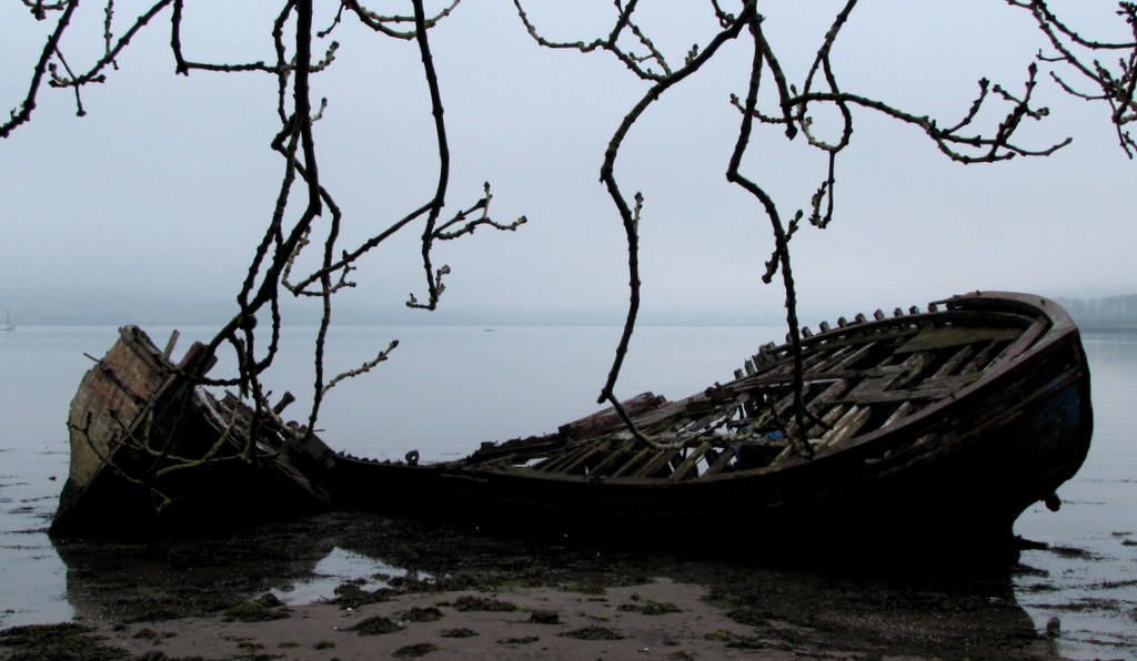 an old row boat sits on the shore next to nches