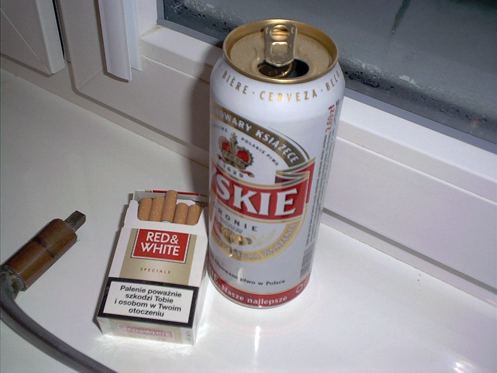 a can of red white and cigarettes on a counter with an opened cigar case