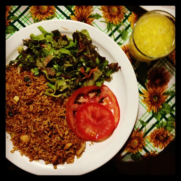 the meal on the plate has tomatoes, lettuce and rice