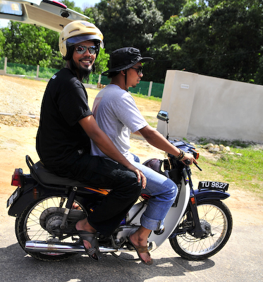 two people are riding on a small motorcycle