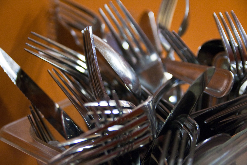 forks and spoons are arranged neatly in a clear cup