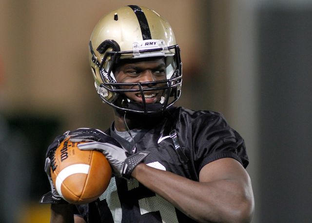 a football player is holding a ball and wearing a helmet