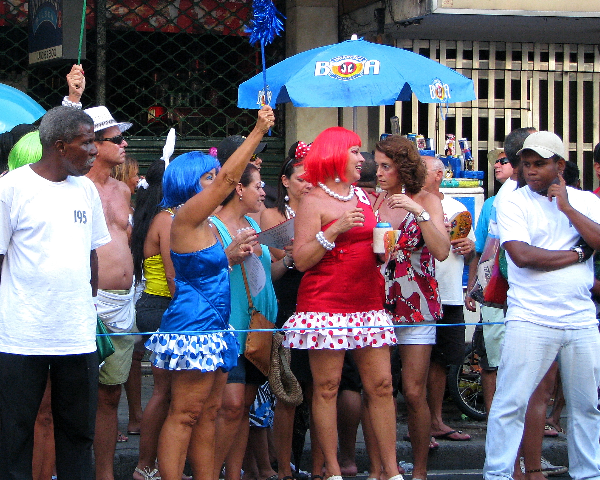 a couple of people in bathing suits holding an umbrella and other people around