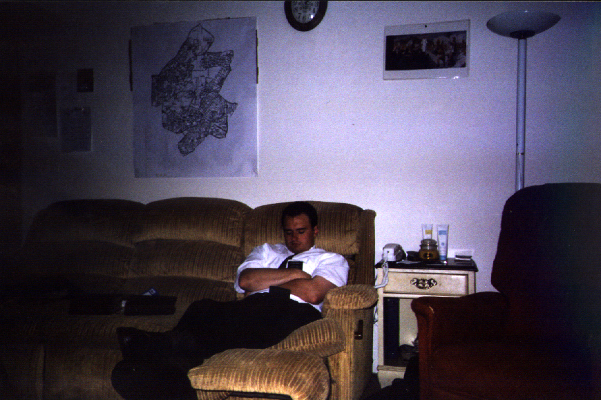 a man sits on a chair next to a wall and a couch