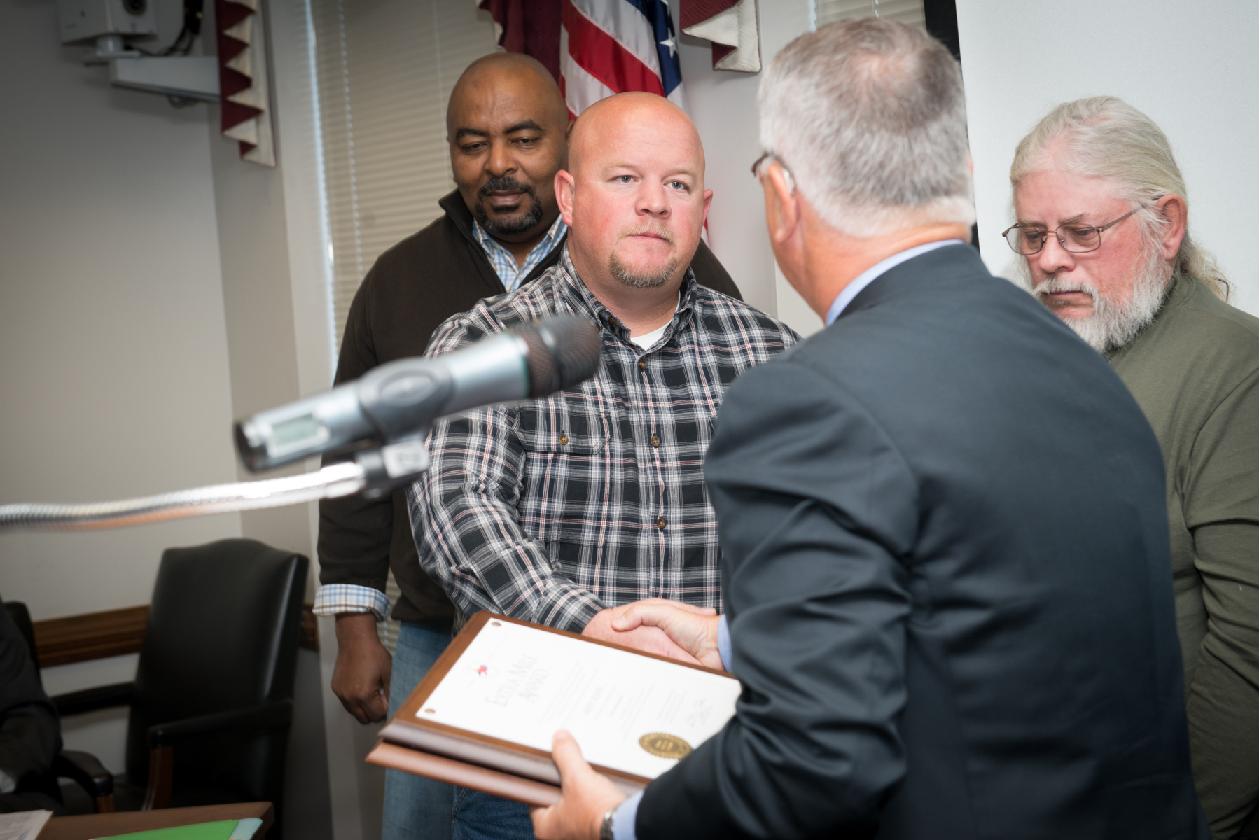 a man being shown to receive a plaque of recognition by several people