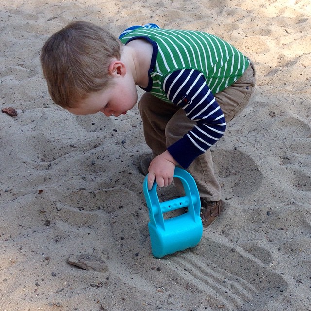 a little boy playing with toys in the sand