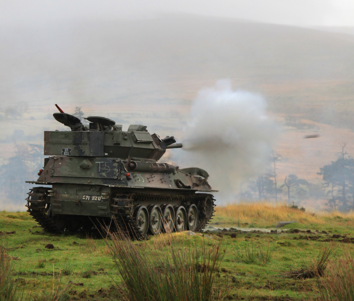 a army tank is moving through the grass