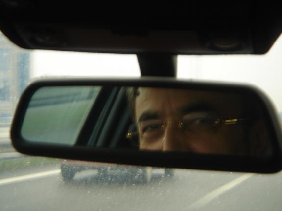 a side mirror with the reflection of a person looking at his reflection