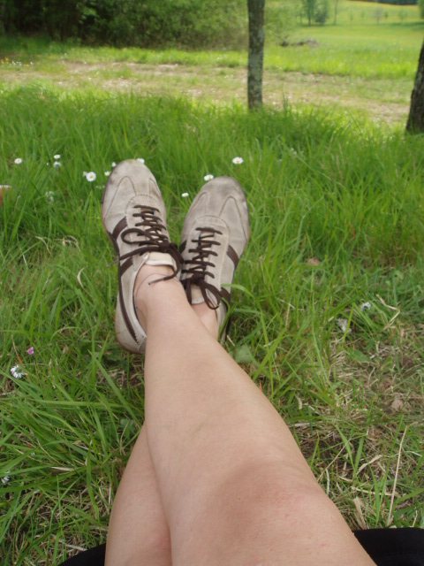 a person's feet resting in the grass on a sunny day