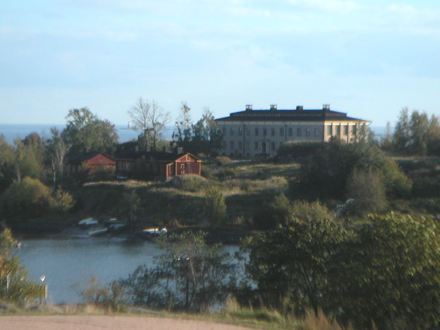 the large house has a white roof and a porch near a lake