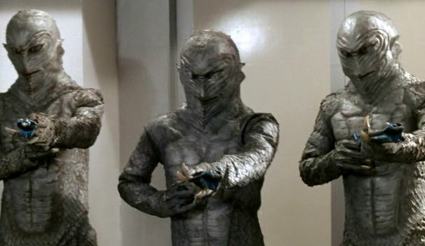 three statues of aliens holding their guns in different angles