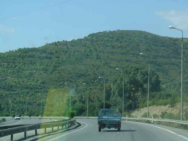 the back of an suv driving down the highway in front of a mountain