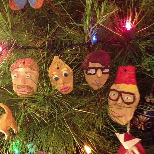 several people faces hanging from the nches of a christmas tree