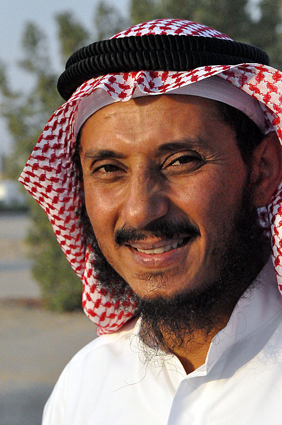 a man in an arab style cap smiles for a po