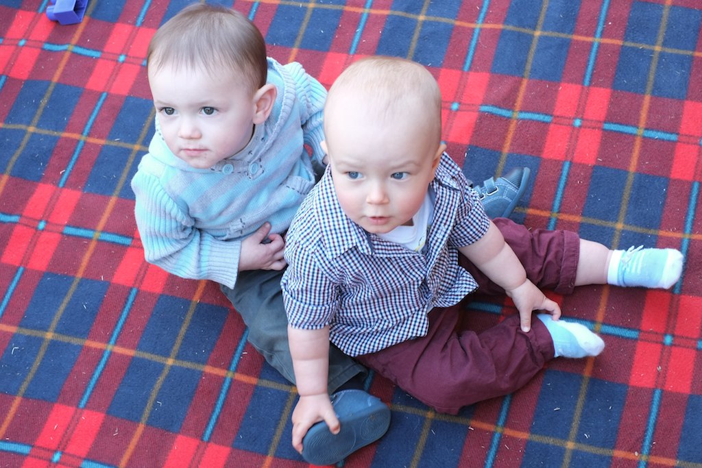 two babies are sitting on a rug in the sun