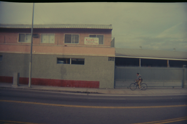 man riding bike on street past building in urban area