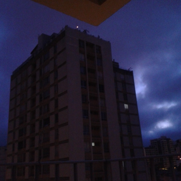 a tall building is lit up against the dark sky