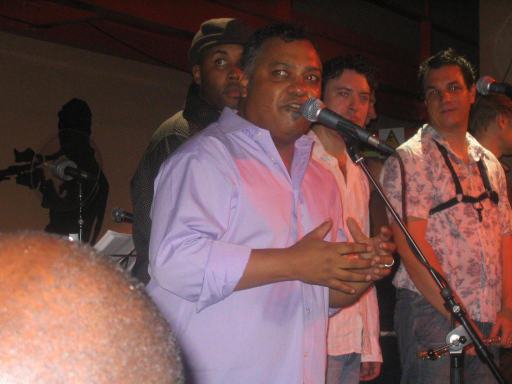 a group of men singing into microphones while people look on