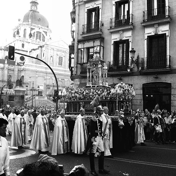 many people are standing on the side walk in front of a group of buildings