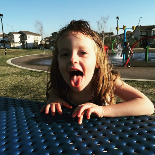 girl making a funny face while laying down on a play ground