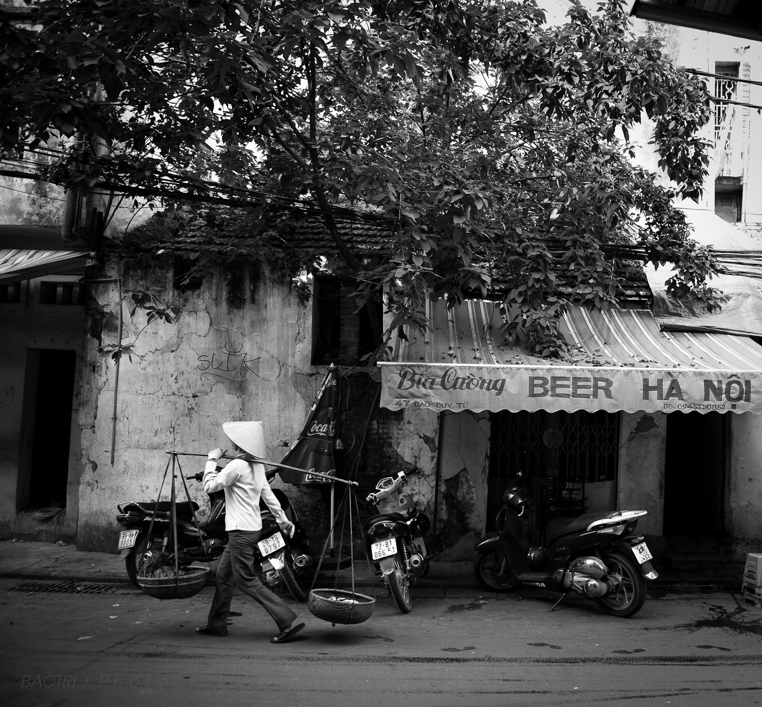 a man walking past an old building with two motorcycles parked in front