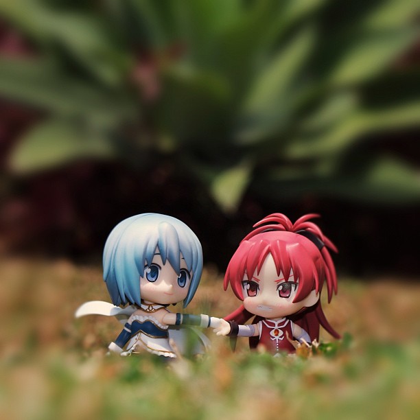 two little anime figures are laying in the grass